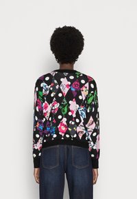 Strikket sweater i sort med flerfarvede blomster- og prikmønstre, ribbede manchetter og kant, samt rund halsudskæring.