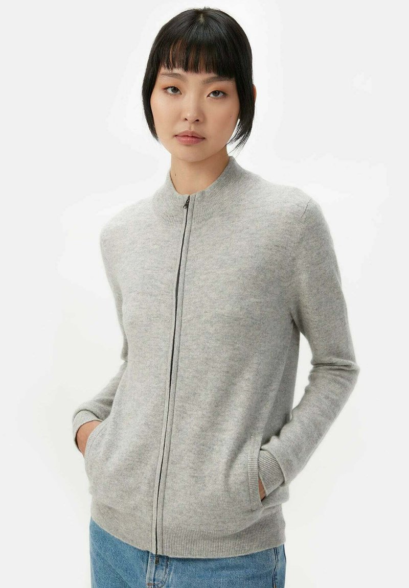 Grå zip-up tröja med rund halsringning, ribbade ärmar och nederkant, tillverkad av ett mjukt, texturerat material. Har sidofickor.