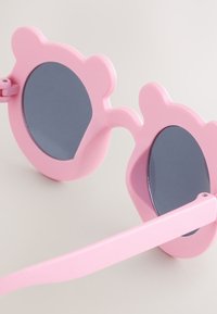 Roze zonnebril met accenten in de vorm van berenoren, cirkelvormige blauw getinte lenzen en een glad kunststof montuur. Heeft een rechte, platte scharnier.