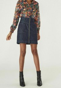 Blommig skjorta med lång ärm och knäppning framtill; jeanskjol med dragkedja framtill, mörkblå färg; bärs med svarta ankelstövlar.