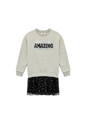 Grijze sweatshirt met een folie "AMAZING" tekstoverlay en een zwarte tule rok met verspreide zilveren sterren. Casual gelaagd ontwerp.