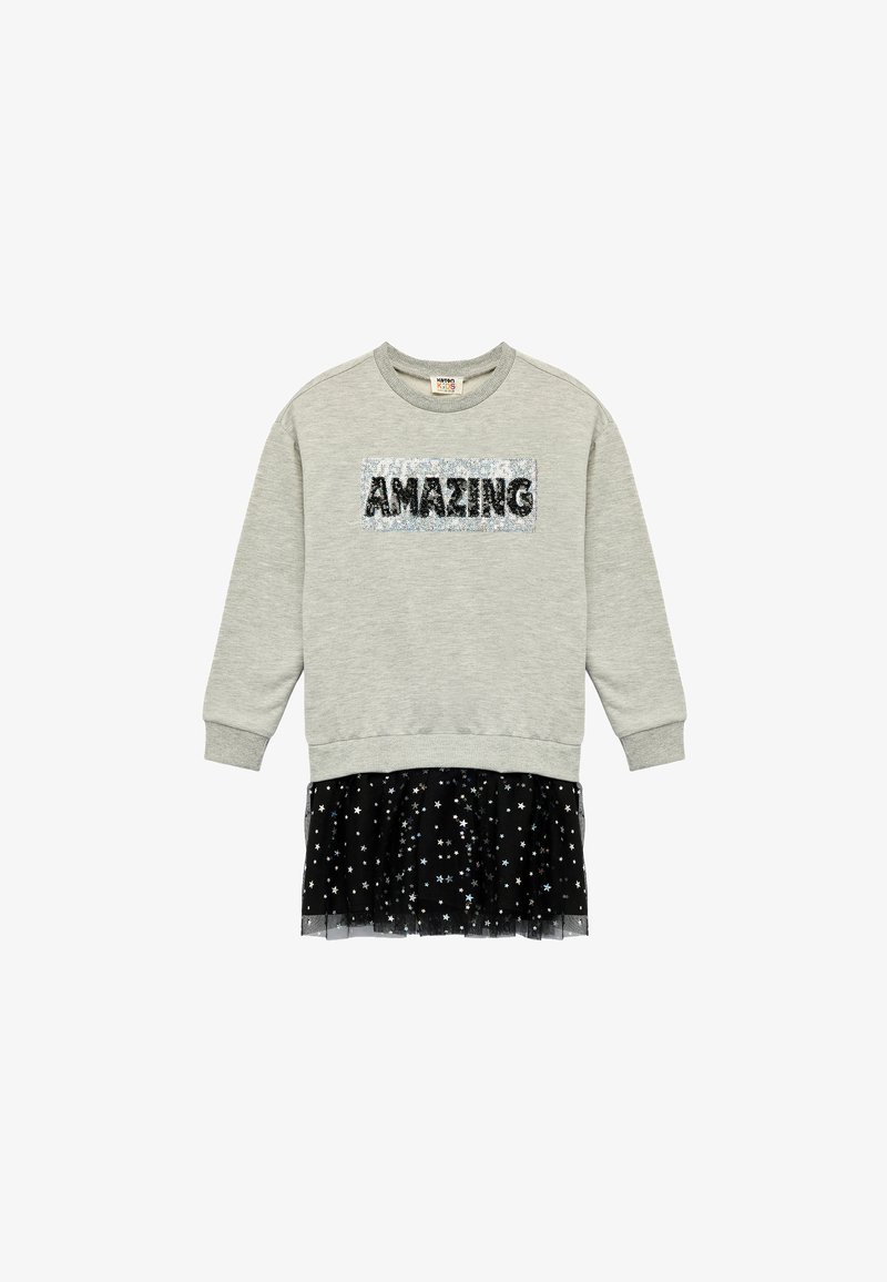 Grå sweatshirt med en paljettöverlagd text "AMAZING" och en svart tylskjol med spridda silverstjärnor. Avslappnad lagerdesign.