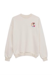 Κρεμ ζακέτα με χαλαρή εφαρμογή, ριγέ μανσέτες και μια μικρή, πολύχρωμη γραφιστική που απεικονίζει μια παλμίδα και αφηρημένα σχήματα στο στήθος.