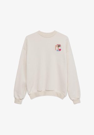 Κρεμ ζακέτα με χαλαρή εφαρμογή, ριγέ μανσέτες και μια μικρή, πολύχρωμη γραφιστική που απεικονίζει μια παλμίδα και αφηρημένα σχήματα στο στήθος.