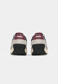 Sneakers featuring a gray upper, navy and maroon accents, textured black outsole, and a visible logo on the heel.