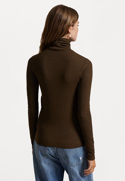 Brauner, gerippter Rollkragenpullover mit langen Ärmeln und enger Passform. Tragen mit blauen, verwaschenen Jeans, zeigt die Rückansicht und die weiche Textur.