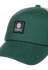 Cappello verde con un design strutturato, caratterizzato da una toppa nera a forma di quadrato e un tessuto testurizzato. La visiera è leggermente curva.