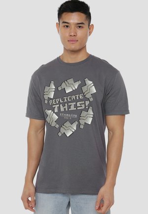 Gray cotton T-shirt featuring metallic silver graphic text and designs, depicting sci-fi elements, with a round neckline and short sleeves.