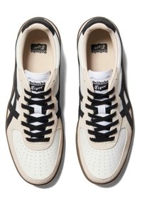 Sneakers Onitsuka Tiger z beżową i czarną cholewką z zamszu i skóry, z czarnymi sznurowadłami, perforowanym przodem i brązową gumową podeszwą.