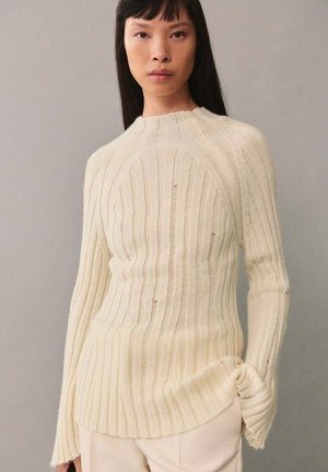Cremfarbener, gerippter Strickpullover mit hohem Kragen, langen Ärmeln und seitlichen Schlitzen für eine lässige Passform. Weiche Textur mit dezenten Variationen.