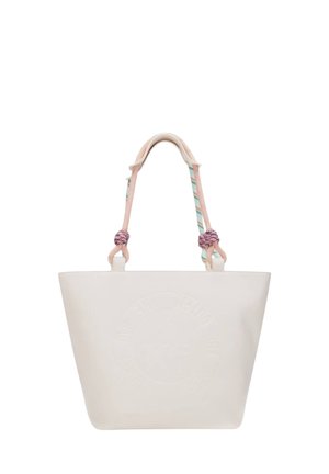 Bolsa de lona crema con logotipo circular en relieve y asas de cuerda rosa pastel anudadas en los puntos de fijación sobre fondo blanco.