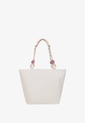 Bolsa de lona crema con logotipo circular en relieve y asas de cuerda rosa pastel anudadas en los puntos de fijación sobre fondo blanco.