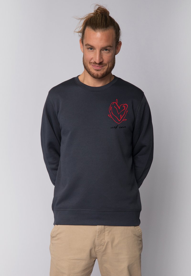 Sweatshirt bleu marine à col rond en coton, avec un graphique de cœur rouge et le texte "amour de soi" à l'avant, avec des manches longues et des poignets côtelés.