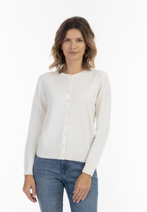 White knit cardigan with a round neckline, featuring a button closure down the front, ribbed cuffs, and a smooth texture. Paired with blue jeans.