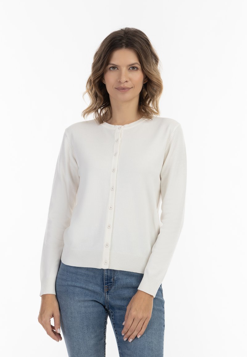Cardigan bianco in maglia con scollatura tonda, dotato di chiusura a bottoni sul davanti, polsini a costine e una texture liscia. Abbinato a jeans blu.