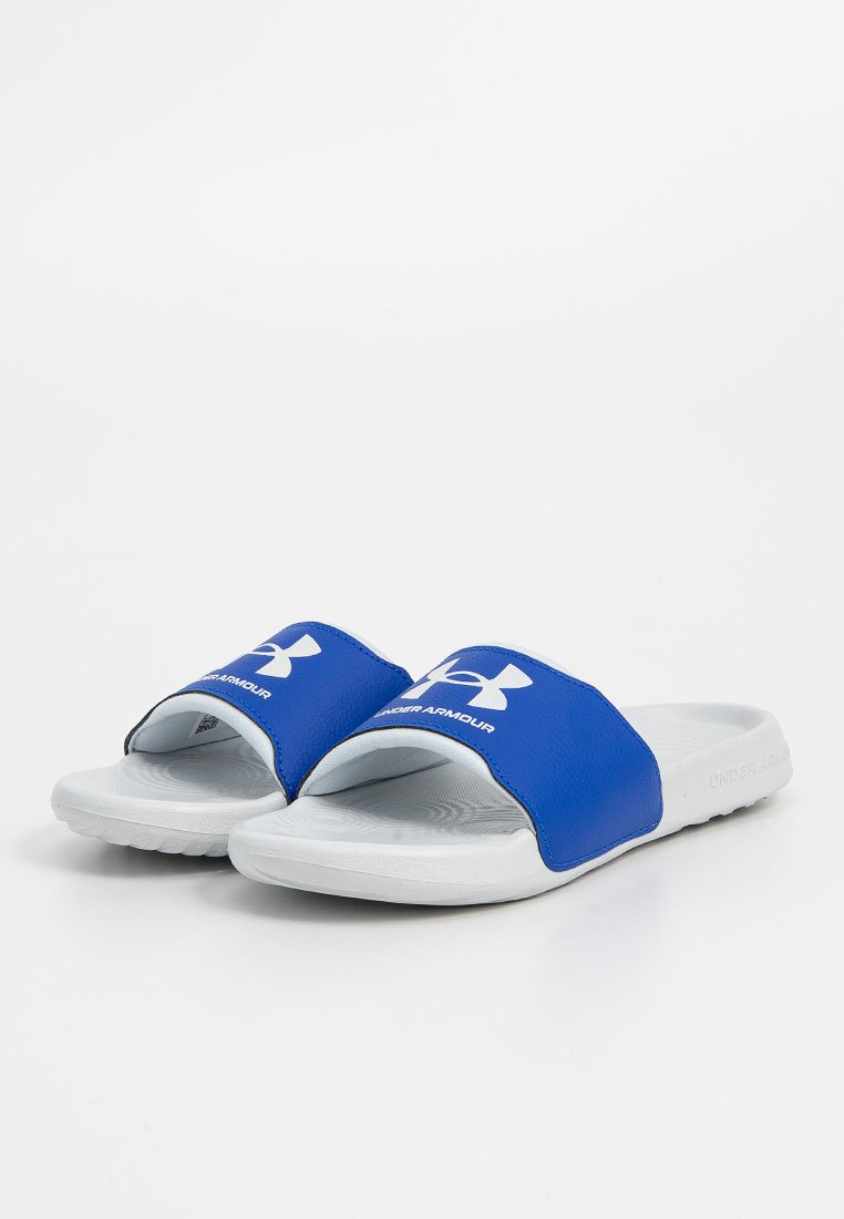 Chanclas azules con una correa ancha y suave que presenta un logo blanco. Suela de goma blanca con una base texturizada para un agarre y confort óptimos.