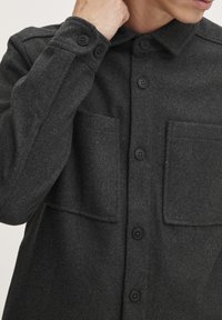 Dunkelgraue Wollmischung Shirtjacke mit Knopfverschluss, zwei Vorderaschen und Kragen. Verfügt über eine glatte Textur und eine taillierte Passform.