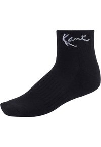 Fekete bokazokni, bordázott anyagból készült, fehér logóval a tetején. A zokni sima felületű és jól meghatározott orrvarrással rendelkezik.