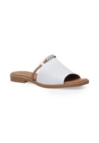 Hvide perforerede slip-on sandaler med en blød brun sål; har en dekorativ accentrem med klare edelsten. Flad, åben-tået design.