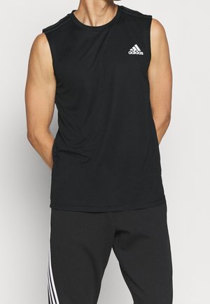 Persona con una camiseta negra sin mangas de Adidas con el logo en el pecho y pantalones negros con rayas blancas a los lados.