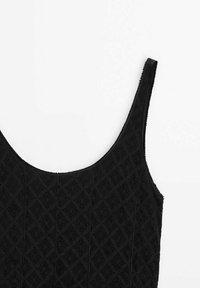 Haut noir sans manches avec motif losange texturé et encolure dégagée sur fond blanc.