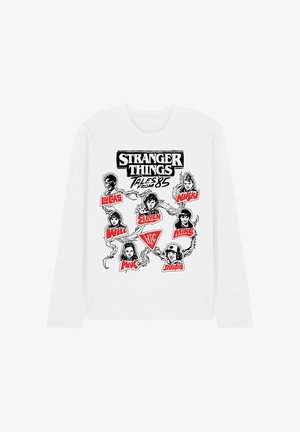 White long-sleeve shirt with black and red "Stranger Things Tales from '85" graphic featuring illustrated character faces and names from the series.