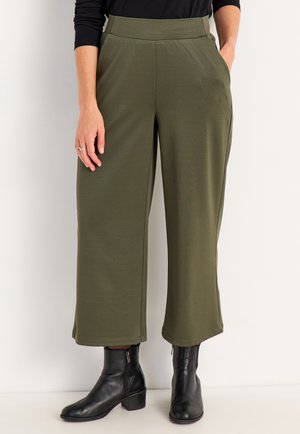 Olijfgroene wijde broek van zachte stof, met zijzakken en een gladde tailleband, gecombineerd met zwarte enkellaarzen.