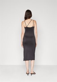 Černé midi šaty bez rukávů s přiléhavým střihem, které mají tenké křížené ramínka na zadní straně a hladkou, elastickou tkaninu.