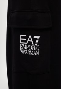 Zwarte sweatshirt met een prominent wit logo op de voorkant. De stof lijkt zacht, met een losse fit en een zakdetail.