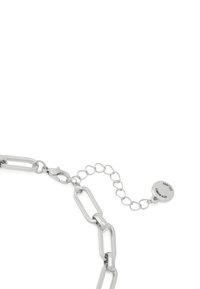 Bracelet en chaîne métallique argentée avec des maillons allongés, équipé d'un fermoir de type homard et d'une chaîne réglable avec une petite plaque ronde pour les variations de taille.