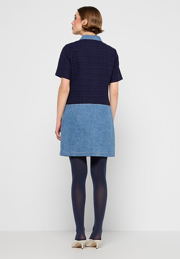 Denimkleid mit einem dunkelblauen strukturierten Oberteil und einem hellblauen Denimrock. Kurze Ärmel, kragenloser Ausschnitt und glattes Material.