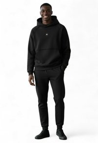 Zwarte hoodie met een brede halslijn en een kort voorpand, gecombineerd met bijpassende taps toelopende broek. Voorzien van een rond logo op de borst.