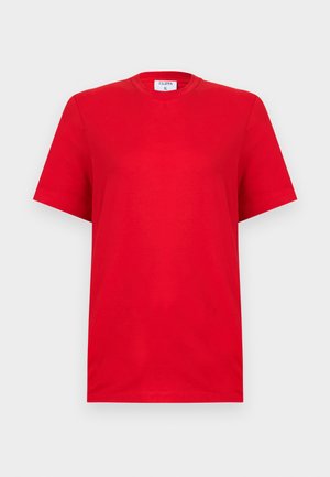 Camiseta lisa roja de manga corta con cuello redondo y etiqueta Filippa K en el interior del cuello, mostrada sobre un fondo gris claro.