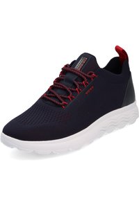 Navy blue mesh sneaker with red accents, textured upper, flexible white sole, and black heel panel. Features red laces and branding.