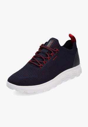 Marineblaue Mesh-Sneaker mit roten Akzenten, strukturiertem Obermaterial, flexibler weißer Sohle und schwarzem Fersenbereich. Mit roten Schnürsenkeln und Branding.