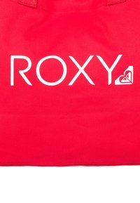Rode canvas tas met het witte logo "ROXY" en een hartontwerp. De textuur is glad met stevige handvatten voor gemakkelijk dragen.