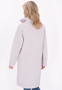 Manteau long lavande clair avec un col haut et des manches longues, présentant une texture douce et une silhouette droite.