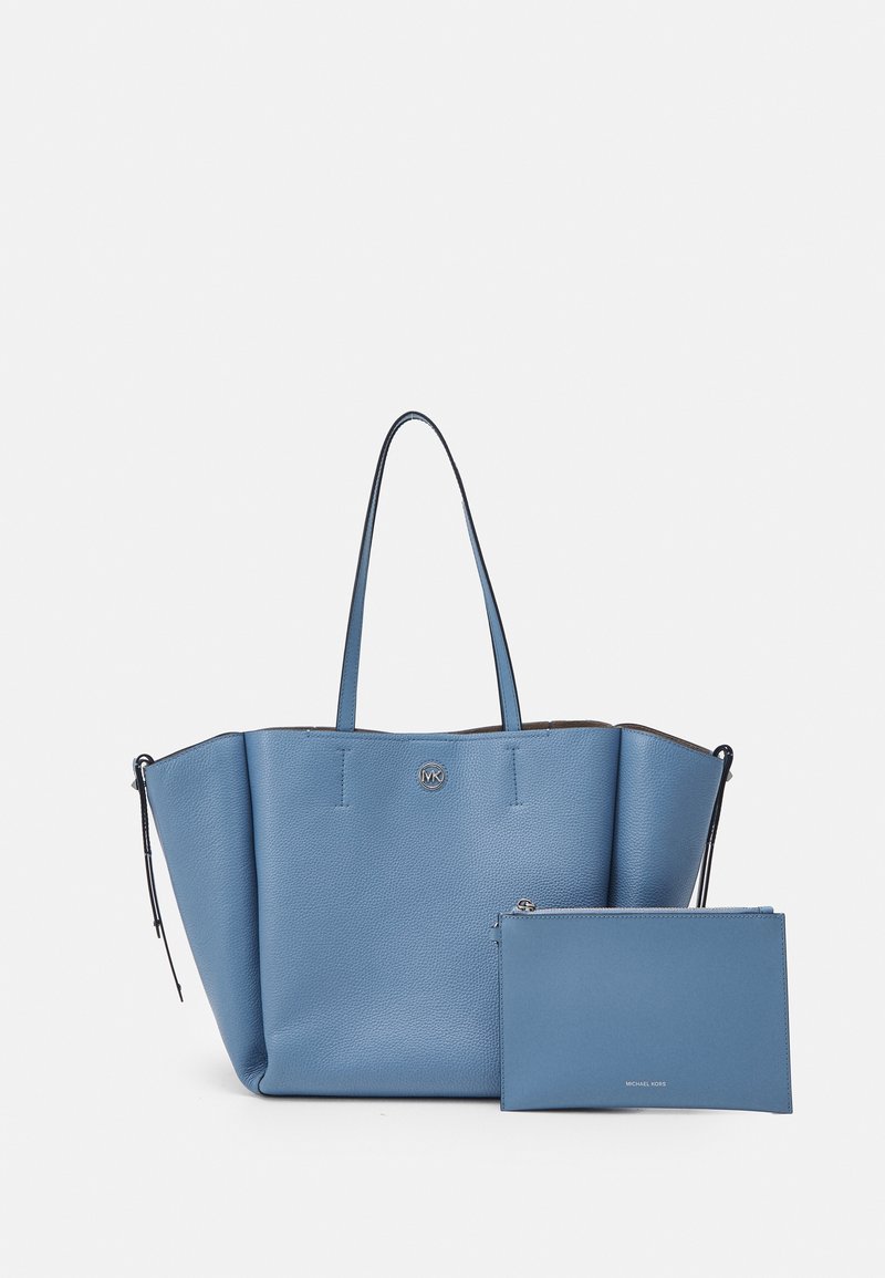Sac cabas en cuir bleu avec deux poignées et une pochette zippée assortie placée devant sur un fond blanc.