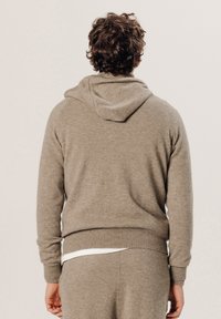Brauner Wollpullover mit einer vorderen Kängurutasche und geripptem Saum. Hat lange Ärmel und ein texturiertes, weiches Material. Rückansicht gezeigt.