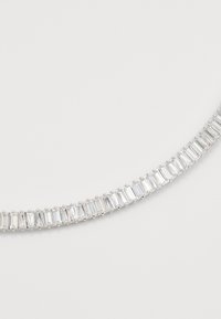 Zilveren ketting met een rij rechthoekige heldere edelstenen die dicht bij elkaar zijn gezet op een effen witte achtergrond.