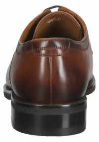 Chaussure en cuir marron avec un bout rond, présentant une texture lisse et des détails de couture subtils. La semelle en caoutchouc noir offre un contraste.