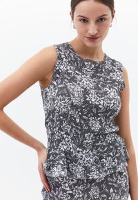 Šedý a bílý bezramínkový top s květinovým vzorem, který má texturovanou tkaninu a peplum lem. Hladký povrch s uvolněnou siluetou.