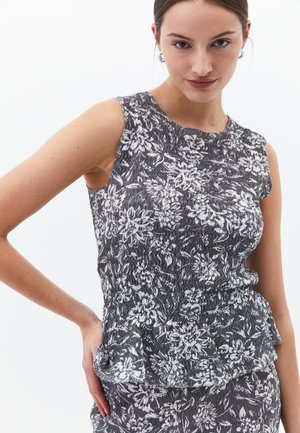 Šedý a bílý bezramínkový top s květinovým vzorem, který má texturovanou tkaninu a peplum lem. Hladký povrch s uvolněnou siluetou.