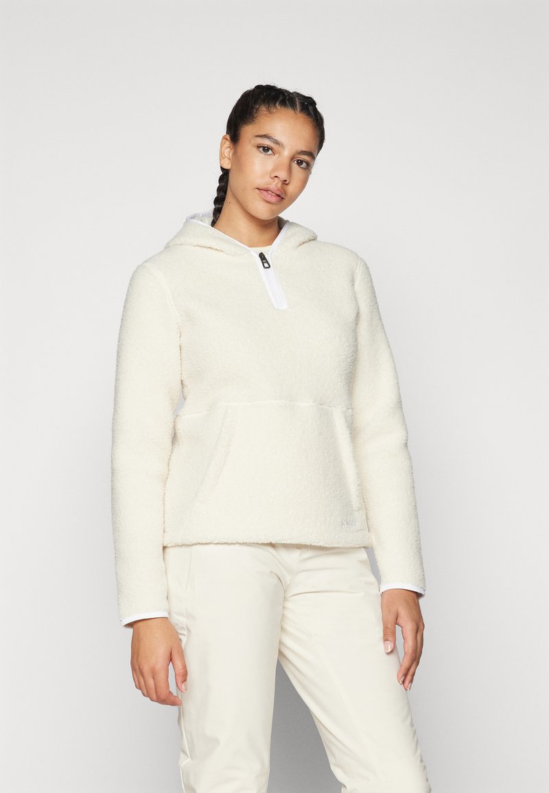 Sweatshirt en polaire couleur crème avec une poche avant, fermeture éclair mi-longue et un revêtement blanc sur le col. Texture douce, coupe décontractée.