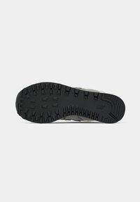 Semelle de chaussure avec des crampons profonds pour la traction et l'adhérence, présentant un motif de crampons et un logo de marque subtil près du talon.