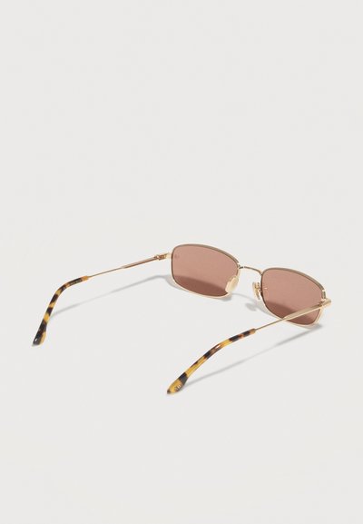 Ορθογώνια γυαλιά ηλίου με λεπτά χρυσά μεταλλικά πλαίσια, φακούς με καφέ απόχρωση και άκρα ναούμ σε μοτίβο χελώνας, σε λευκό φόντο.