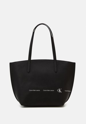 Zwarte leren totebag met een getextureerd oppervlak, dubbele handvatten en bedrukte accenten van het 'Calvin Klein Jeans' logo op de voorkant.