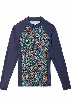 Bluză de protecție cu mâneci lungi, cu guler cu fermoar, mâneci de culoare bleumarin închis și un model floral în roșu, portocaliu, albastru și verde pe trunchi.