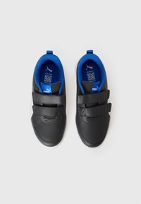 Baskets de sport noires avec une tige en cuir lisse, doublure en tissu bleu et deux bandes Velcro. Semelle en caoutchouc blanche notable.