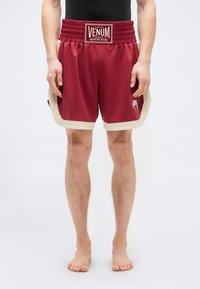 Μπορντό αθλητικό σορτς με μπεζ λεπτομέρειες. Διαθέτει ελαστική μέση με το λογότυπο "VENUM" και πλαϊνές σχισμές για ευκινησία. Ομαλή υφή, ελαστική εφαρμογή.